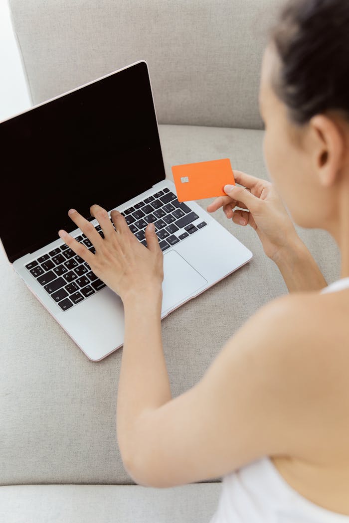 Woman holding credit card making online purchase on laptop computer, representing e-commerce.